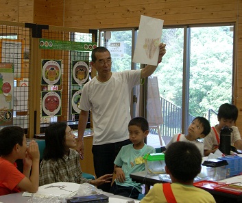 写真：子どもが描いた絵を掲げる松岡さん