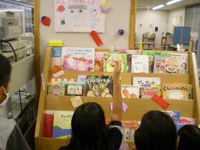画像:北図書館での子ども司書活動の様子。自分たちで作ったフェアの資料を見る子どもたち。